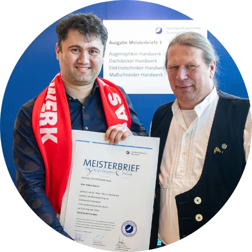 Foto von Zimmerer- und Dachdeckermeister Akbar Venn bei der Meisterbriefübergabe zum Dachdeckermeister, neben ihm sein Ausbilder